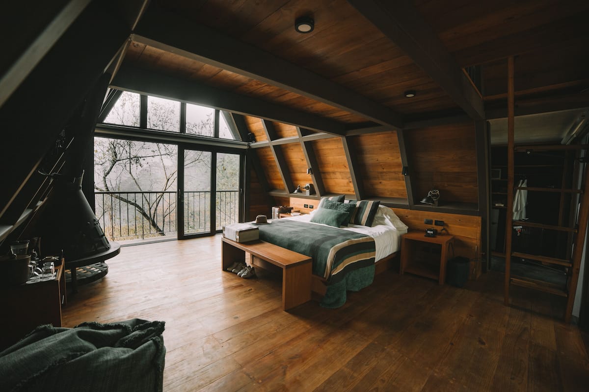 Un dormitorio acogedor con un ventanal grande, muebles de madera y una estantería empotrada.