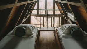 A room with two beds aligned in the center, wooden beams, and a large window at the end of the room. - Santo Cielo by Casa Santo Domingo (Antigua Guatemala)