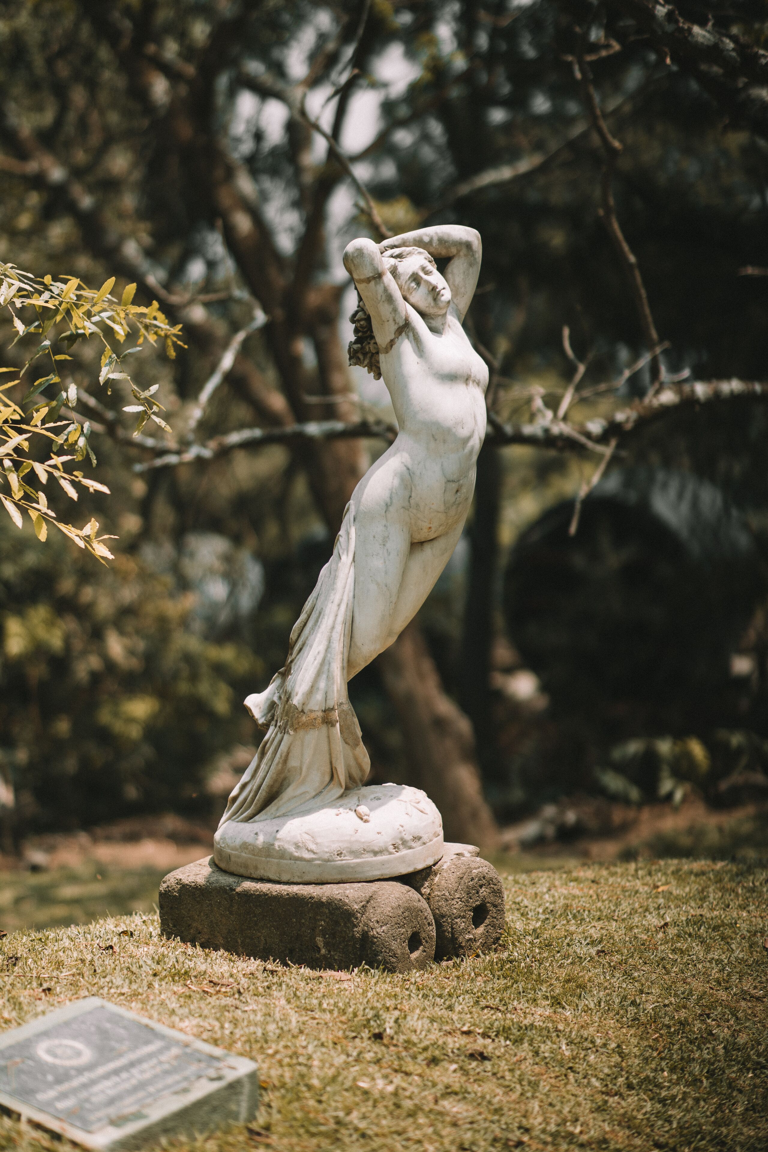 A statue of a woman in a garden setting.
