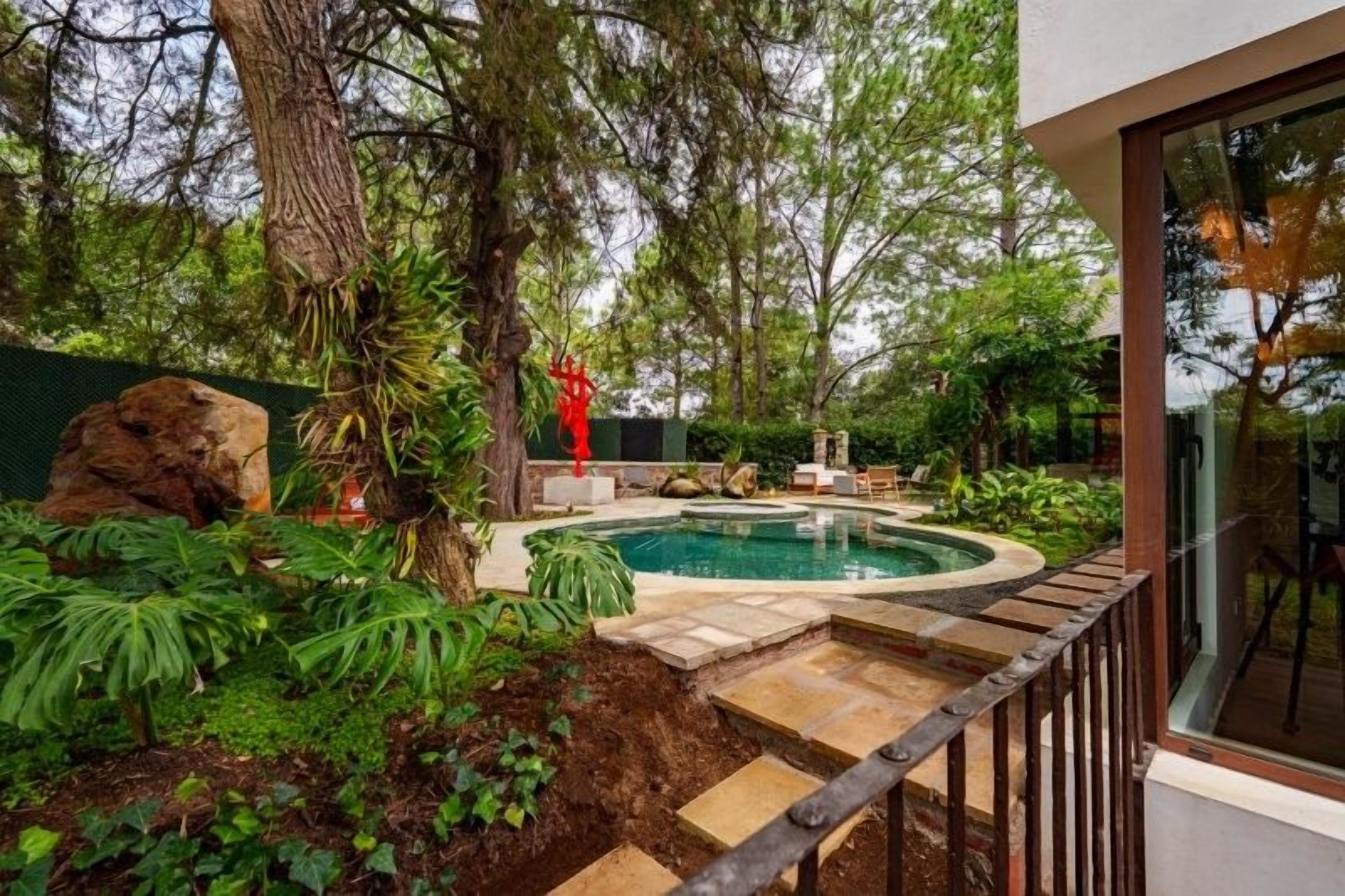 A swimming pool surrounded by lush greenery and a stone deck.