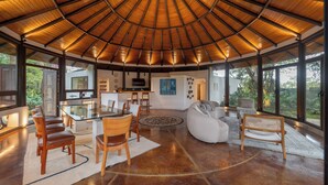 A spacious living area with a high ceiling, a glass dining table, and comfortable seating. - Santo Cielo by Casa Santo Domingo (Antigua Guatemala)