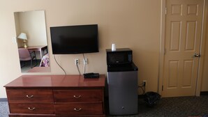 A hotel room with a wooden dresser, a flat-screen TV, a microwave, and a door. - Twilite Motel & RV Park (Prince Albert)