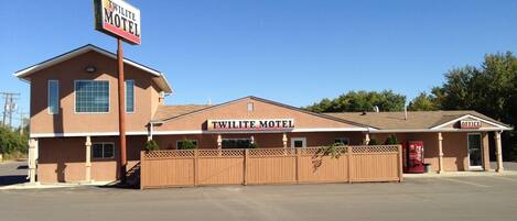 A two-story motel with a prominent sign, a fenced parking area, and a Coca-Cola vending machine.
