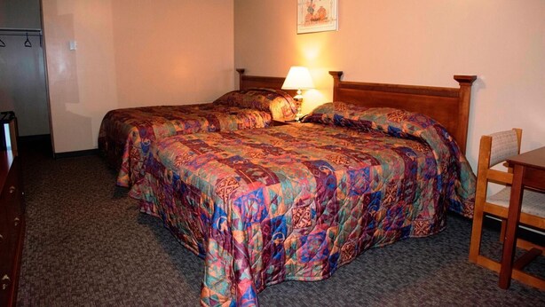 A hotel room with two beds, a wooden headboard, a desk, and a chair. - Twilite Motel & RV Park (Prince Albert)