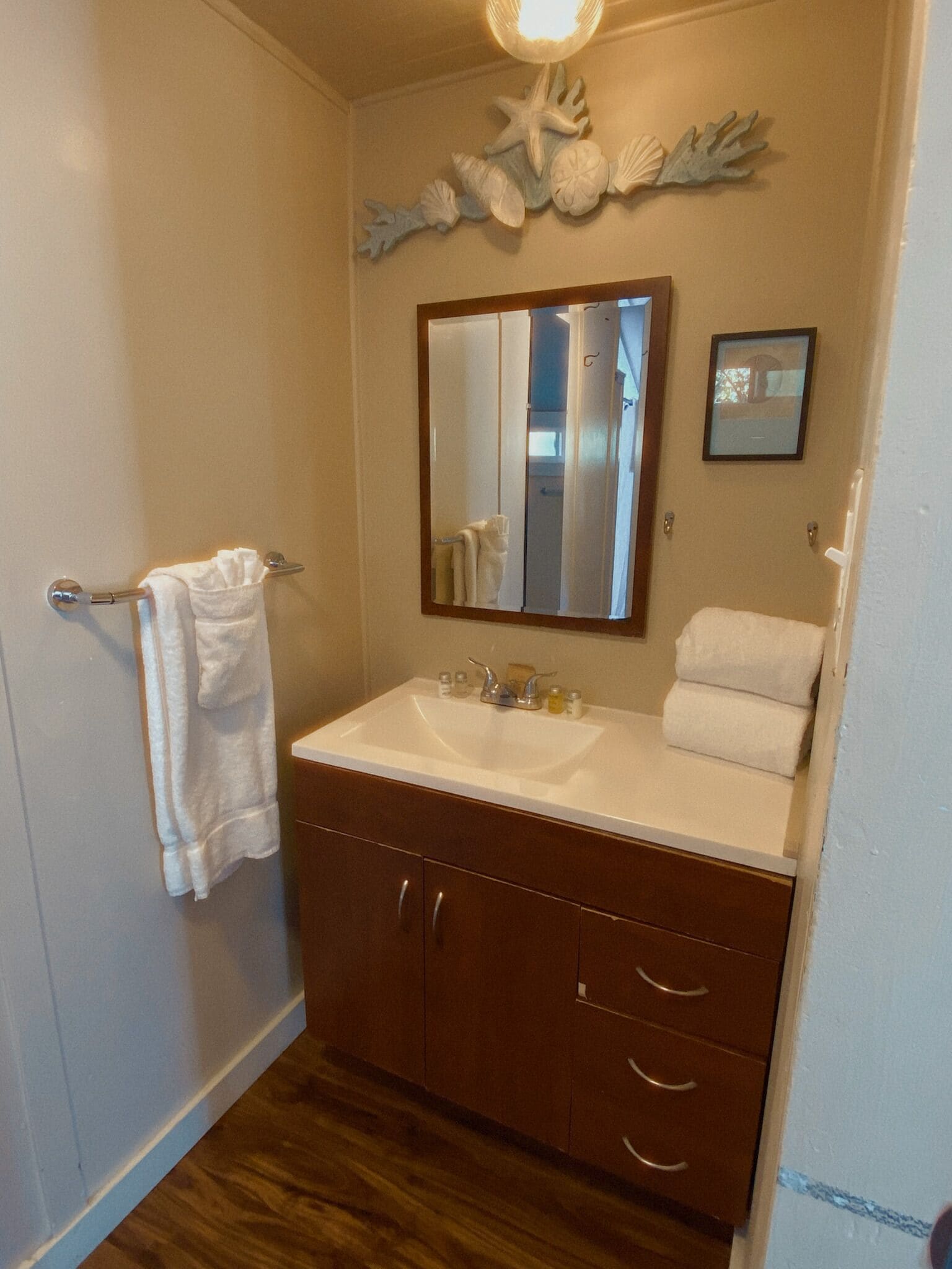 Une salle de bain avec un lavabo blanc, des meubles en bois, un miroir et un porte-serviettes.