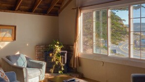 Een ruime woonkamer met een hoge plafond, een groot rondboogvenster en een open haard.