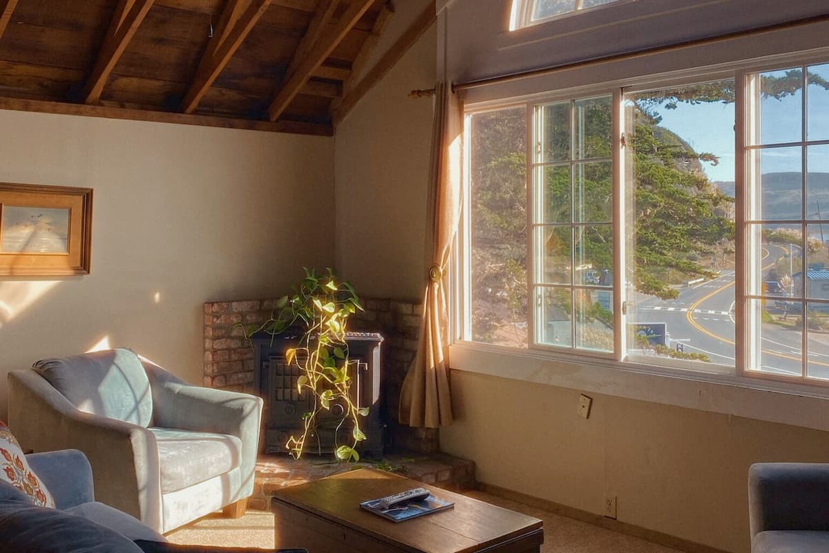 A spacious living room with a high ceiling, a large arched window, and a fireplace.
