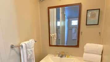 Un baño con lavamanos blanco, espejo y un adorno decorativo sobre el espejo.