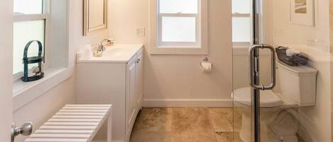 Un baño moderno con cabina de ducha de vidrio, un lavamanos blanco y un inodoro.