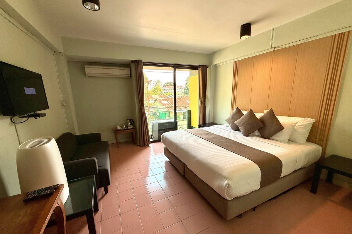 A hotel room with a bed, a desk, a chair, a television, and a window with curtains.