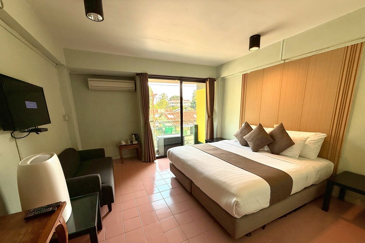 A hotel room with a bed, a desk, a chair, a television, and a window with curtains.