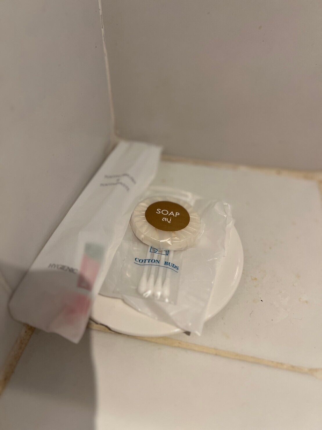 Un baño con un lavabo blanco, una pastilla de jabón, hisopos y una caja de pañuelos blancos.