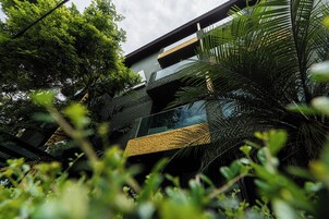 A modern building with a glass facade, surrounded by lush greenery.