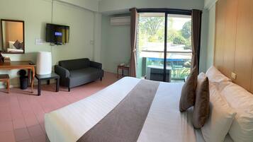 A hotel room with a bed, a sofa, a desk, a television, and a view of the outdoors.