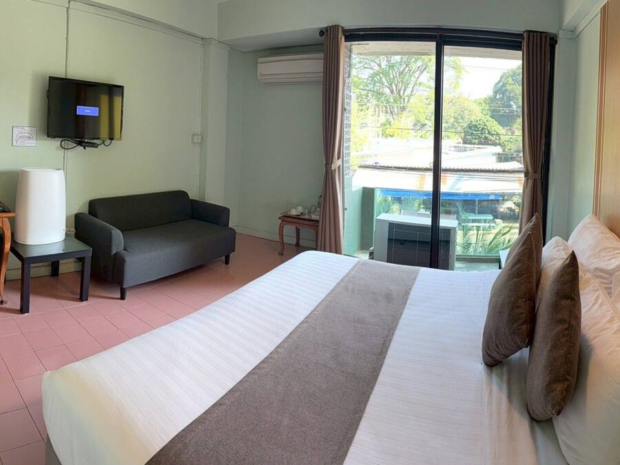 A hotel room with a bed, a sofa, a desk, a television, and a view of the outdoors.