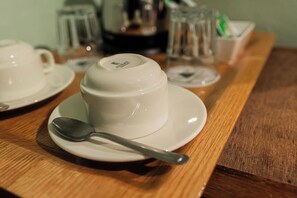 Una tetera blanca sobre una mesa de madera con una cuchara al lado.