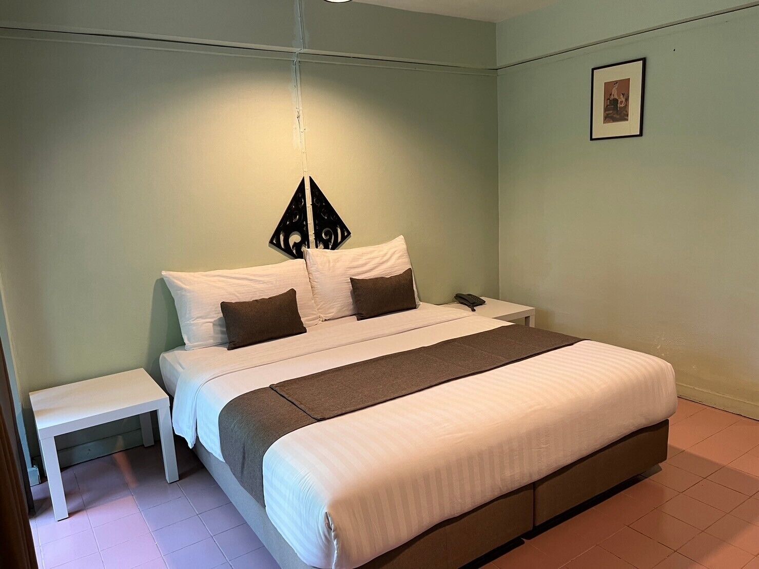 Een keurig opgemaakt slaapkamer met een bed, nachtkastje en een hanglamp.