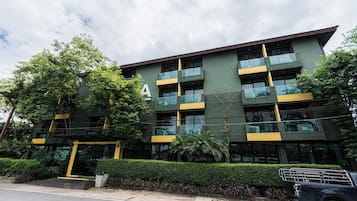 A multi-story building with a green facade, multiple balconies, and a large entrance.