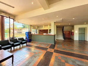 A hotel lobby with a reception desk, seating area, and a staircase. - A Hotel Budget (Chiang Saen)