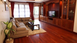 Una sala de estar con un sofá, una mesa de centro, un televisor, armarios de madera y una planta en maceta.