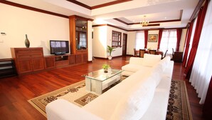 Un salón amplio con un sofá grande, una mesa de centro de vidrio y un televisor.