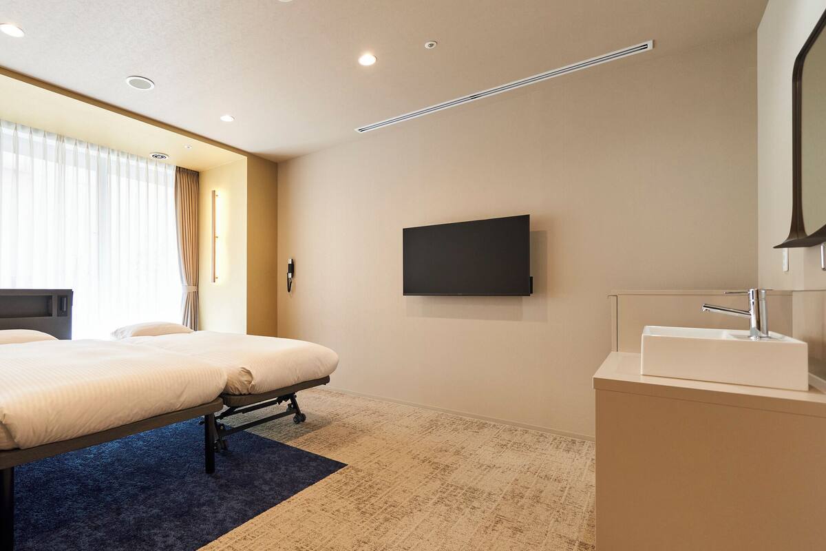 A hotel room with a bed, a TV, and a bathroom with a sink.