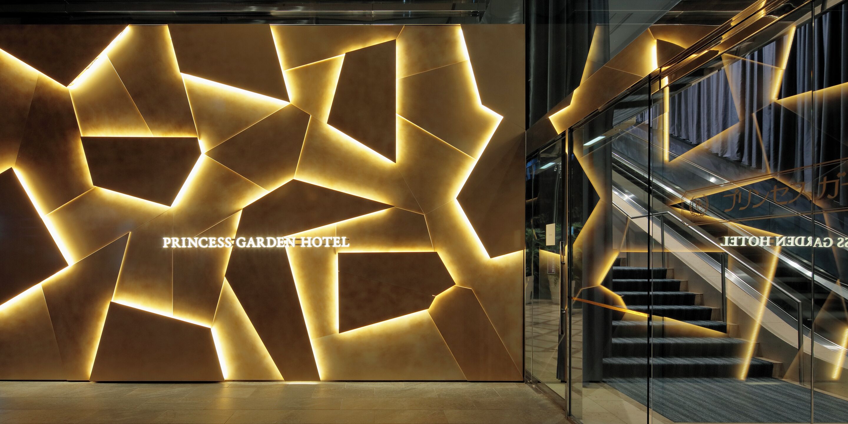 Un vestíbul d'hotel modern amb dissenys geomètrics a la paret i una escala.