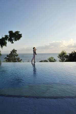 Una piscina al aire libre, sombrillas, sillones reclinables de piscina