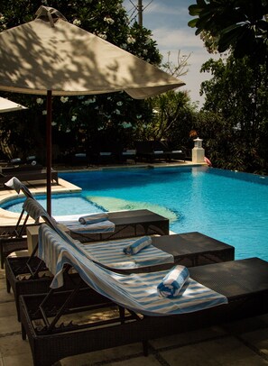 A pool area with lounge chairs and an umbrella. - Anda Amed Resort (Karangasem)