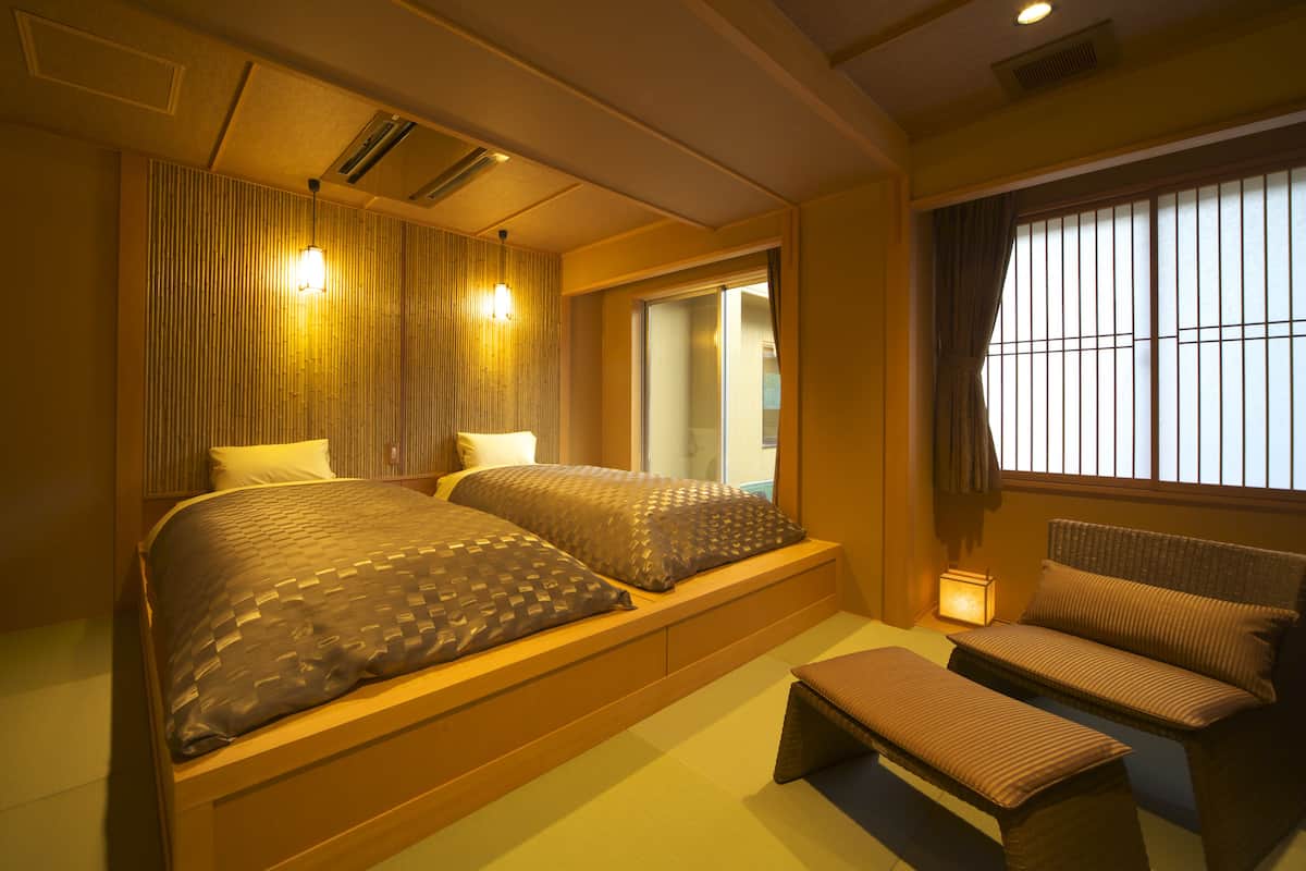 A bedroom with a large bed, bedside tables, a small sofa, and a window with curtains.