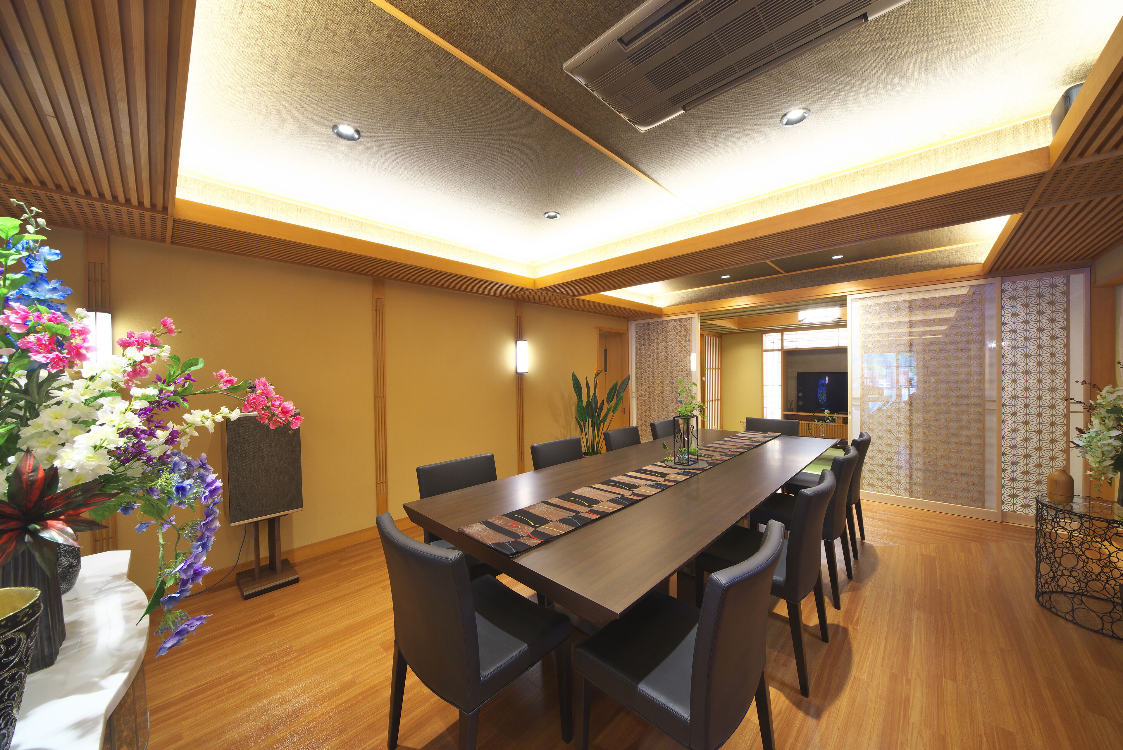 A conference room with a long table, chairs, and a decorative plant.