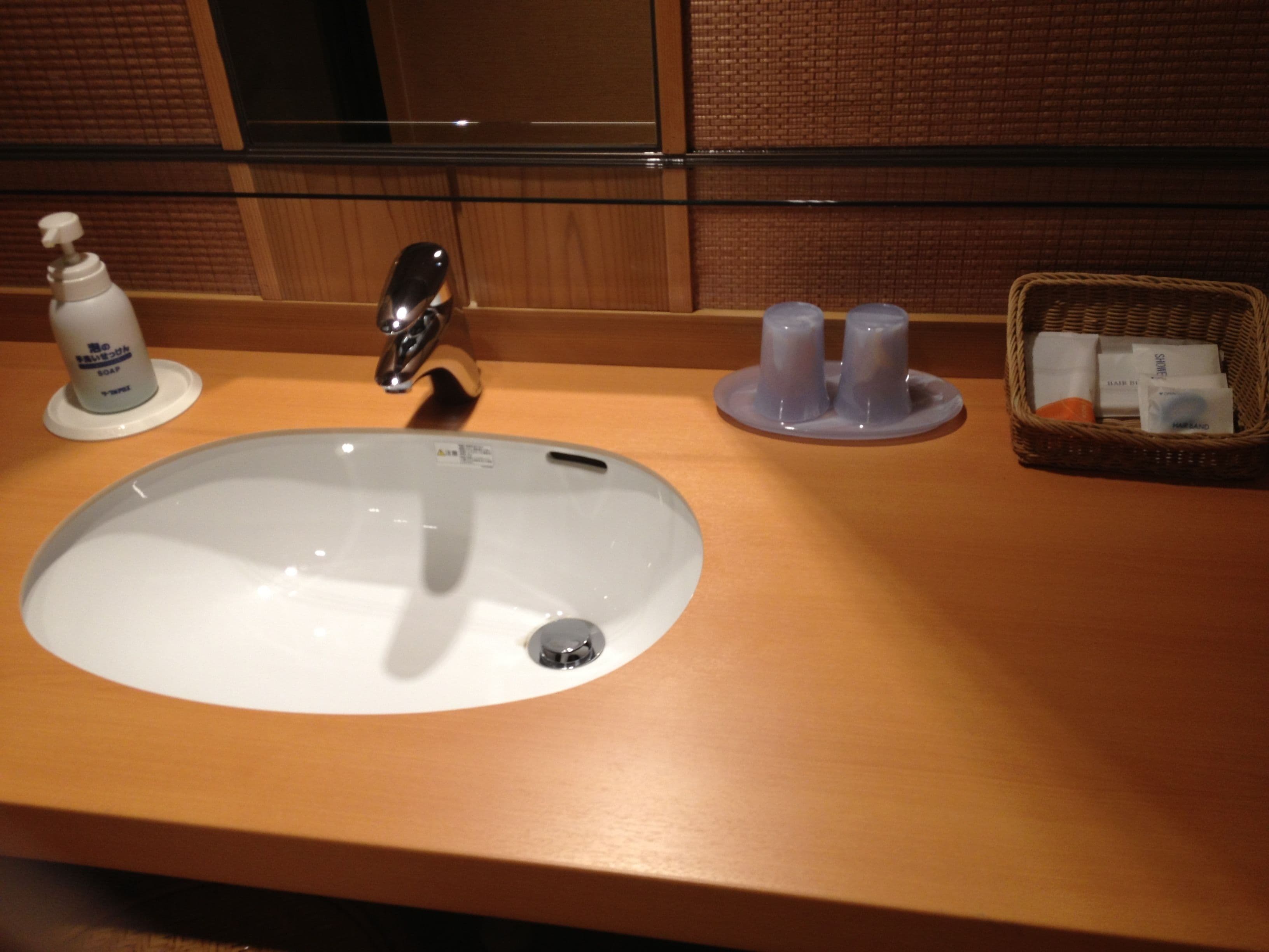 A bathroom sink with a soap dispenser, a faucet, and a small basket with toiletries.