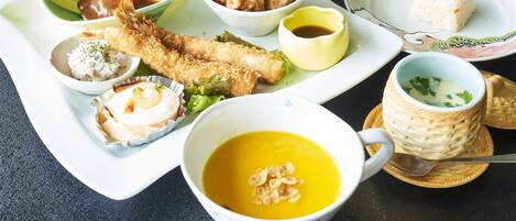 A variety of dishes including fried items, rice, and soup, served on multiple plates and bowls.