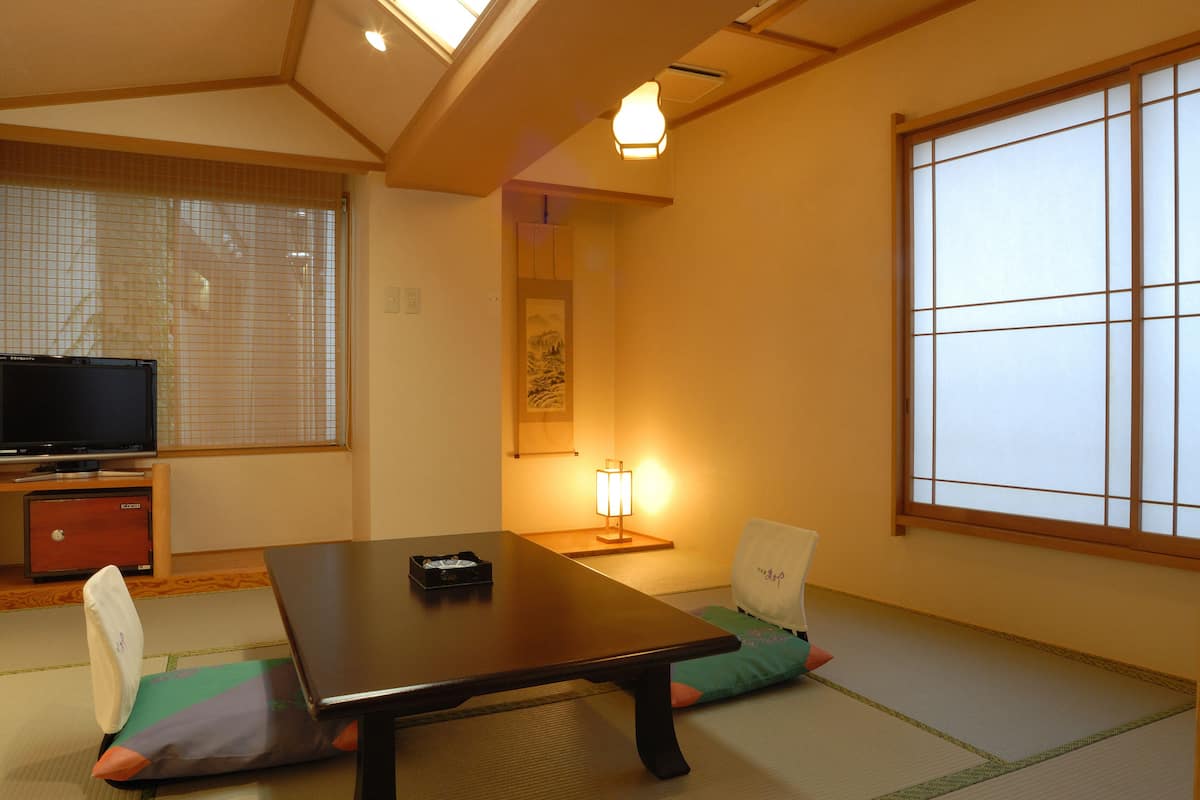 A traditional Japanese room with tatami flooring, a low table, a television, and a sliding door.