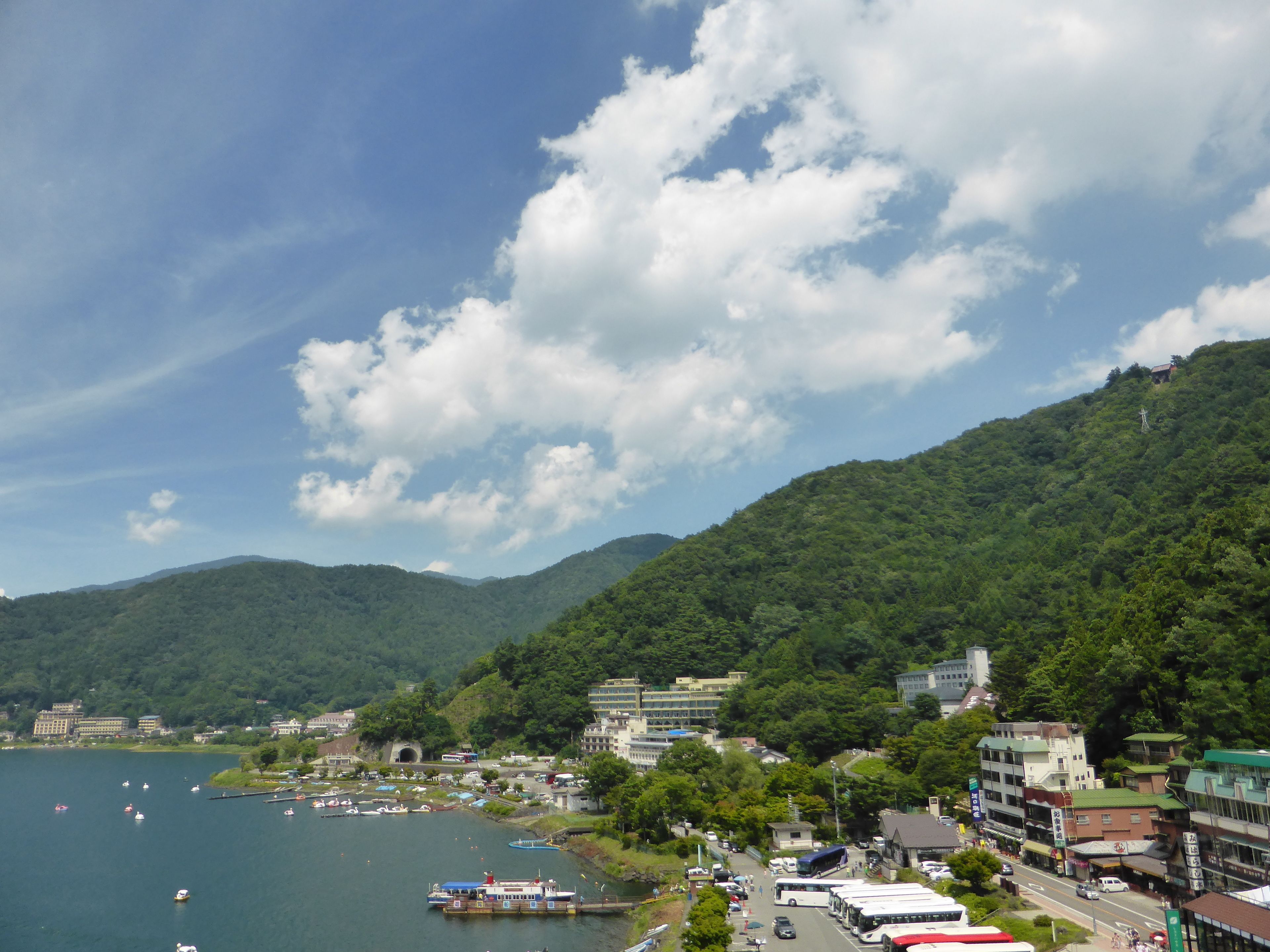 Un pueblo costero con un puerto deportivo, barcos y un paisaje montañoso de fondo.