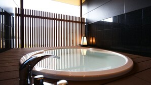 A modern bathroom with a round bathtub, a wooden floor, and a wall-mounted towel rack. - Kasuitei Ohya (Fujikawaguchiko)