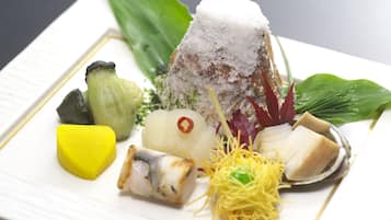 A plate of assorted food items including a mound of rice, a piece of fish, and various vegetables.