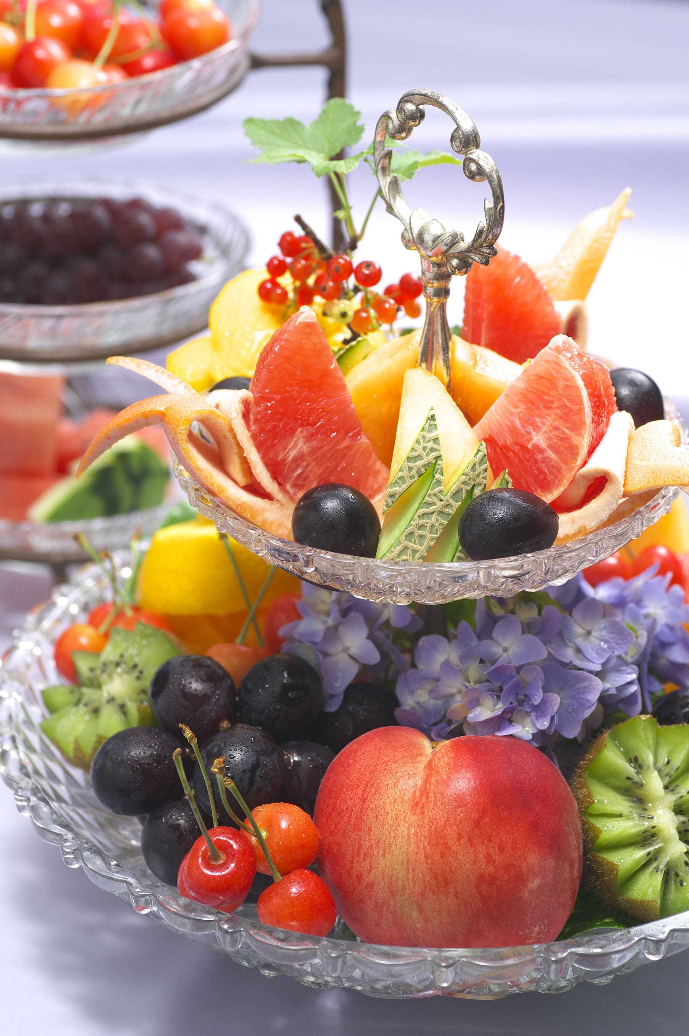 A multi-tiered fruit display with various fruits and berries.