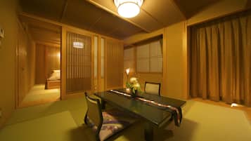 Una habitación japonesa tradicional con suelo de tatami, una mesa baja con un jarrón de flores, puertas correderas y un biombó de papel.