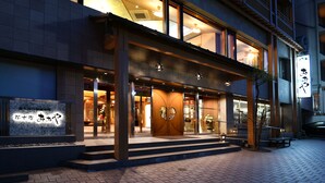 A hotel entrance with a wooden facade, large glass windows, and a sign with Japanese characters. - Kasuitei Ohya (Fujikawaguchiko)