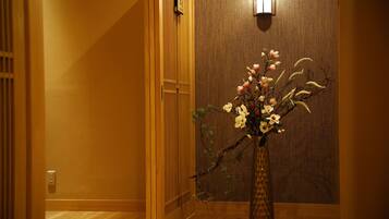 A hallway with a wooden floor, a wooden door, and a wall-mounted light fixture.