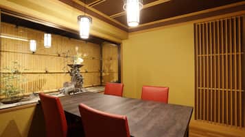 A conference room with a long table, red chairs, and hanging lights.