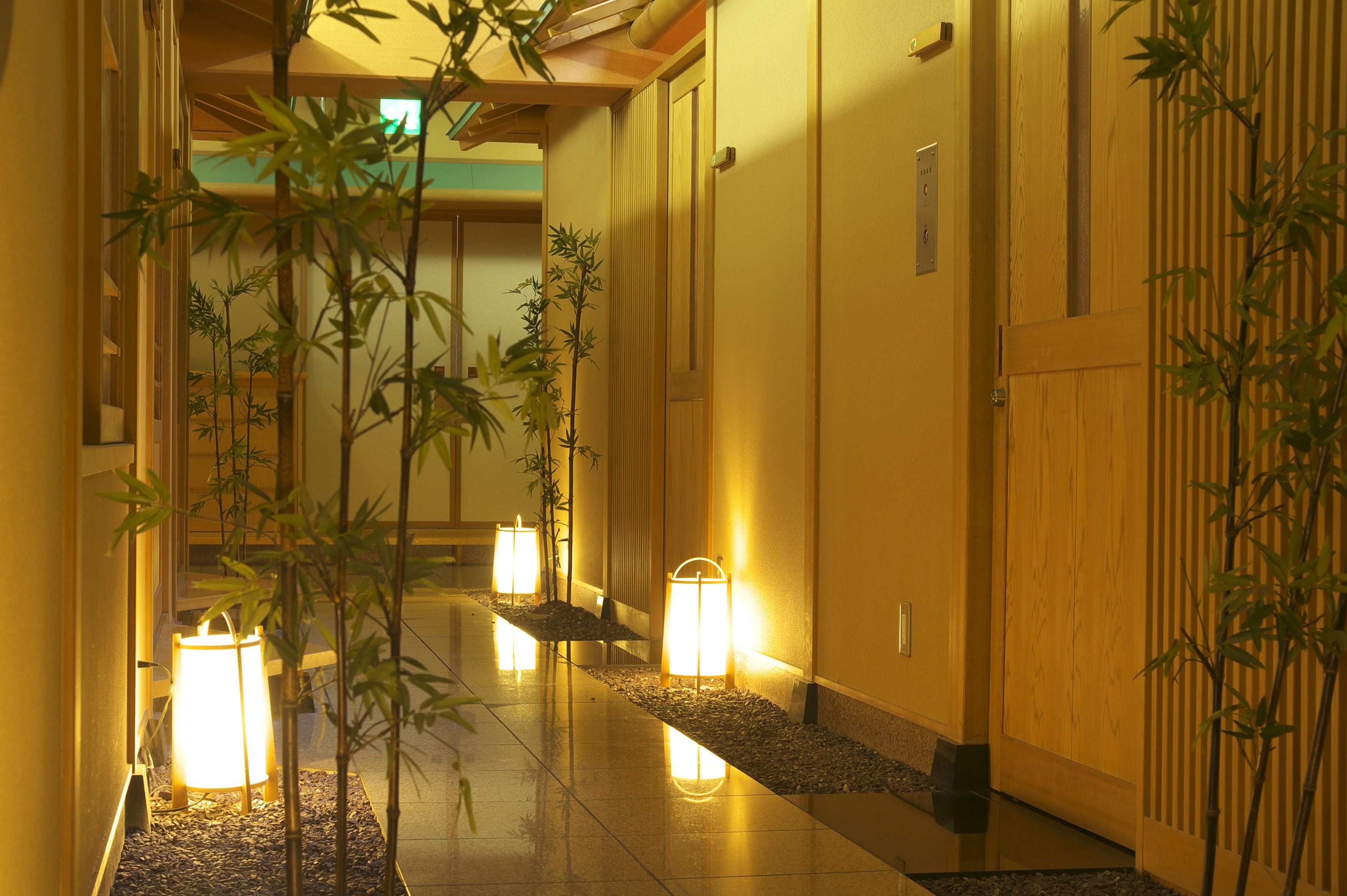 Un couloir décoré dans un style traditionnel, avec des plantes en bambou et des portes en bois.