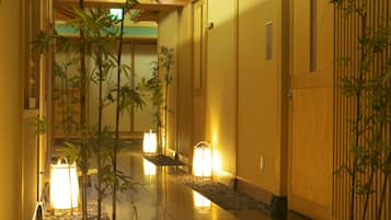 A hallway with traditional decor, including bamboo plants and wooden doors.