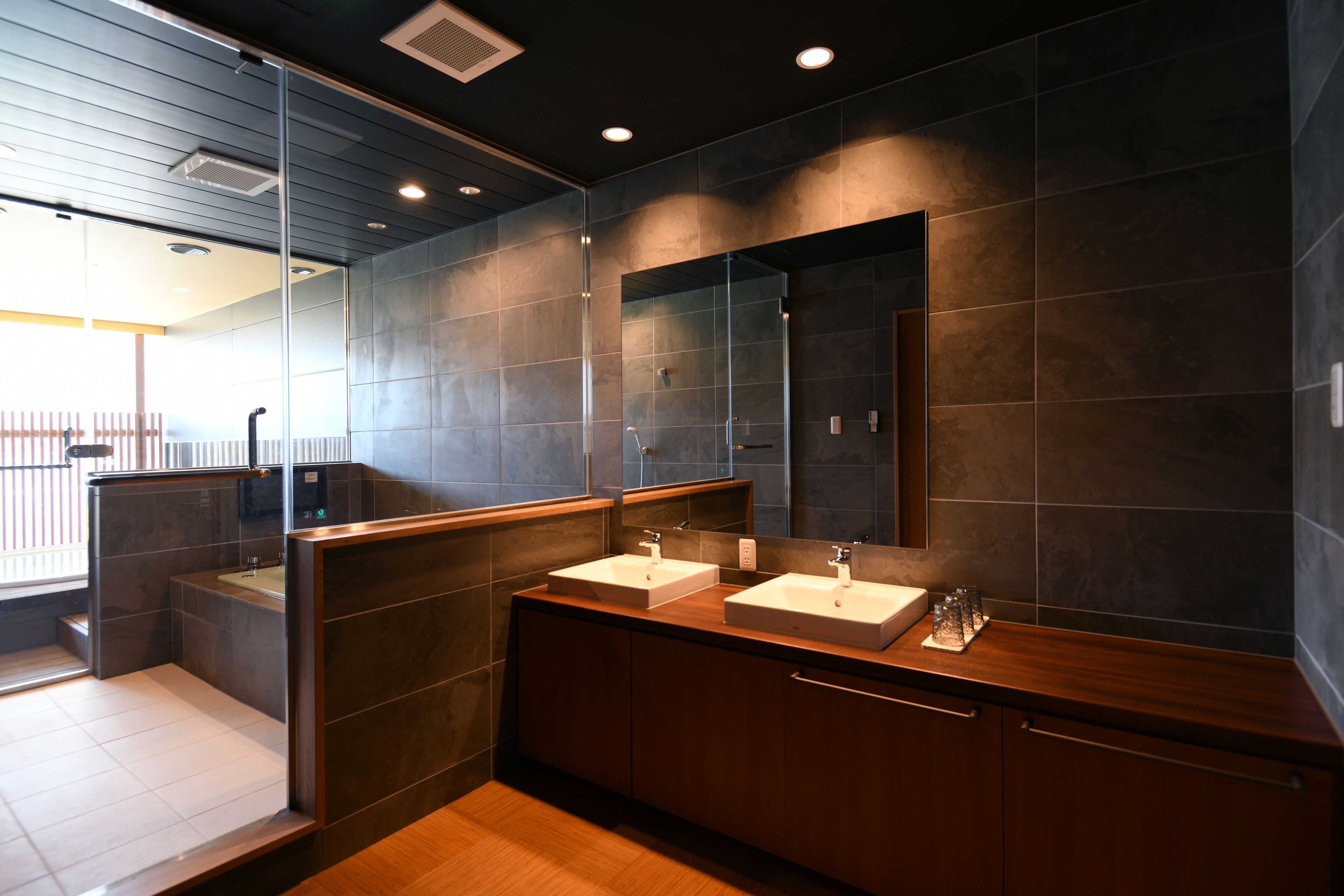 Une salle de bain moderne avec deux vasques, un grand miroir et un meuble-lavabo en bois.