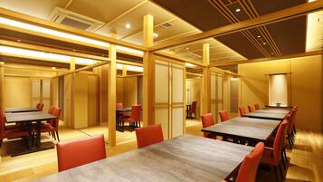 A conference room with multiple tables and chairs, wooden paneling, and recessed lighting.