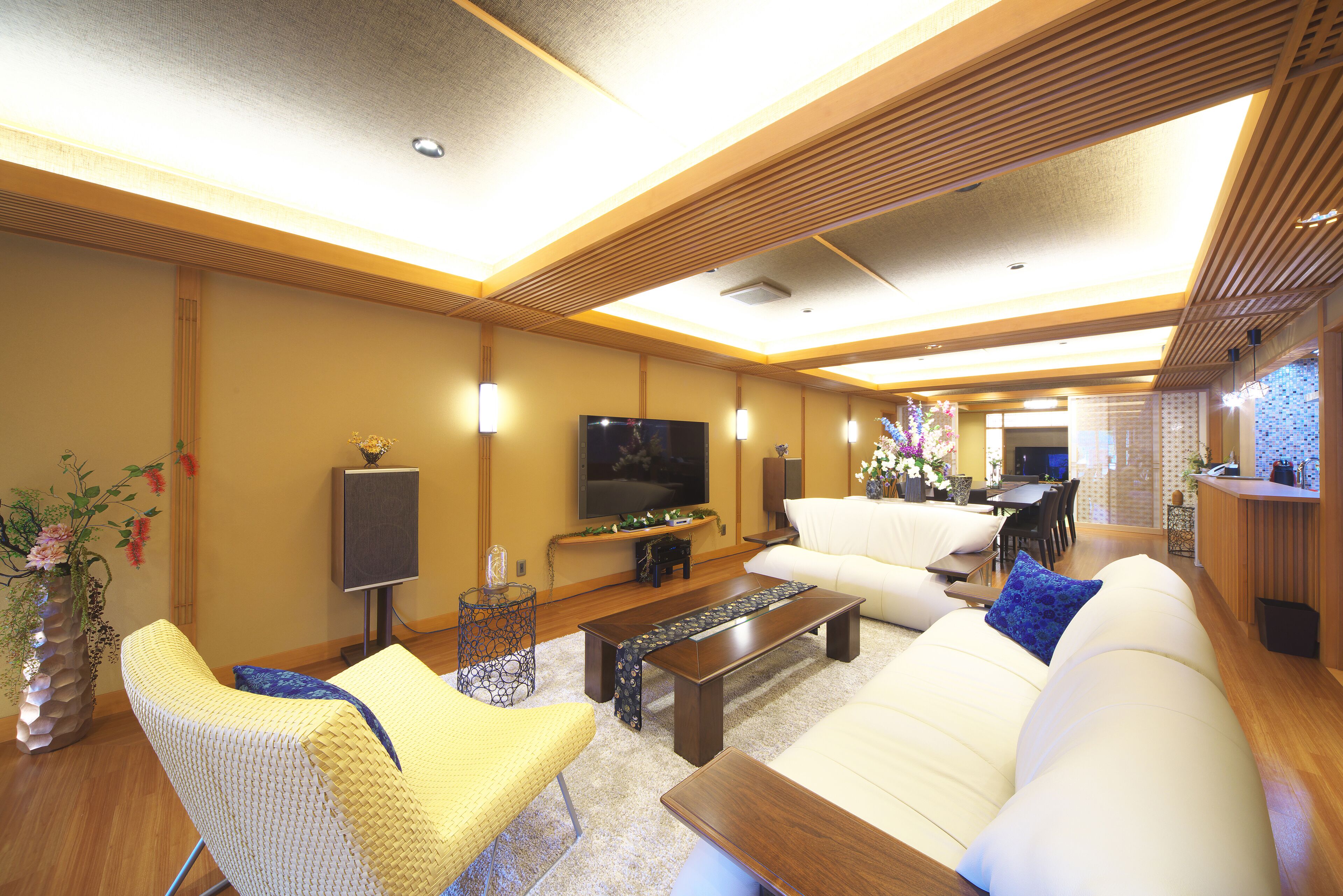 Una sala moderna con sofá, sillón y mesa de centro, televisor de pantalla plana y comedor con mesa y sillas.