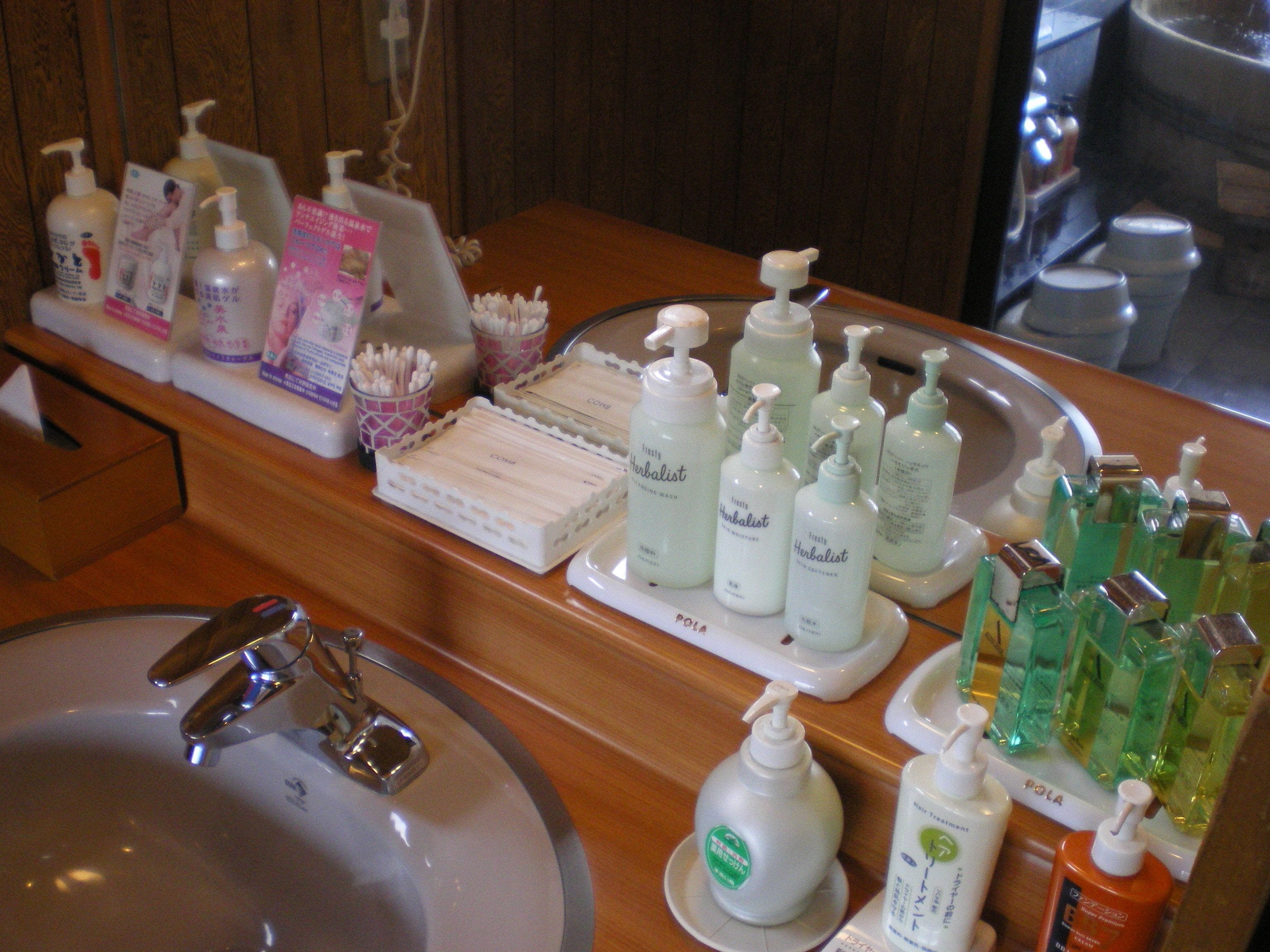 A hotel reception area with a wooden counter displaying various toiletries and a sink.