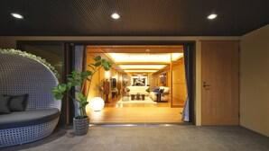 A modern interior with a curved seating area, a potted plant, and a hallway leading to a room with a sofa and a table. - Kasuitei Ohya (Fujikawaguchiko)