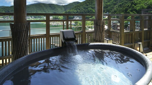 A hot tub under a wooden pergola with a view of a lake and mountains. - Kasuitei Ohya (Fujikawaguchiko)